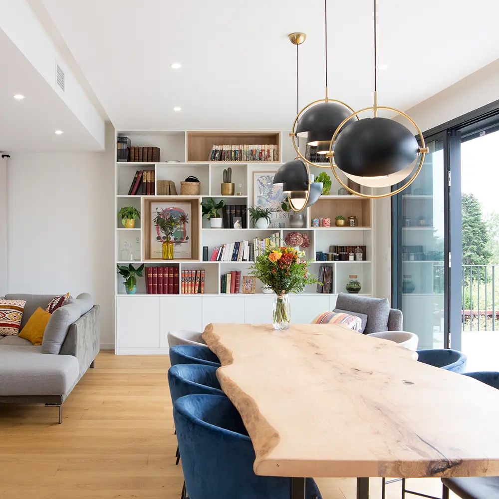 Intérieur avec table bois, bibliothèque et grande baie vitrée