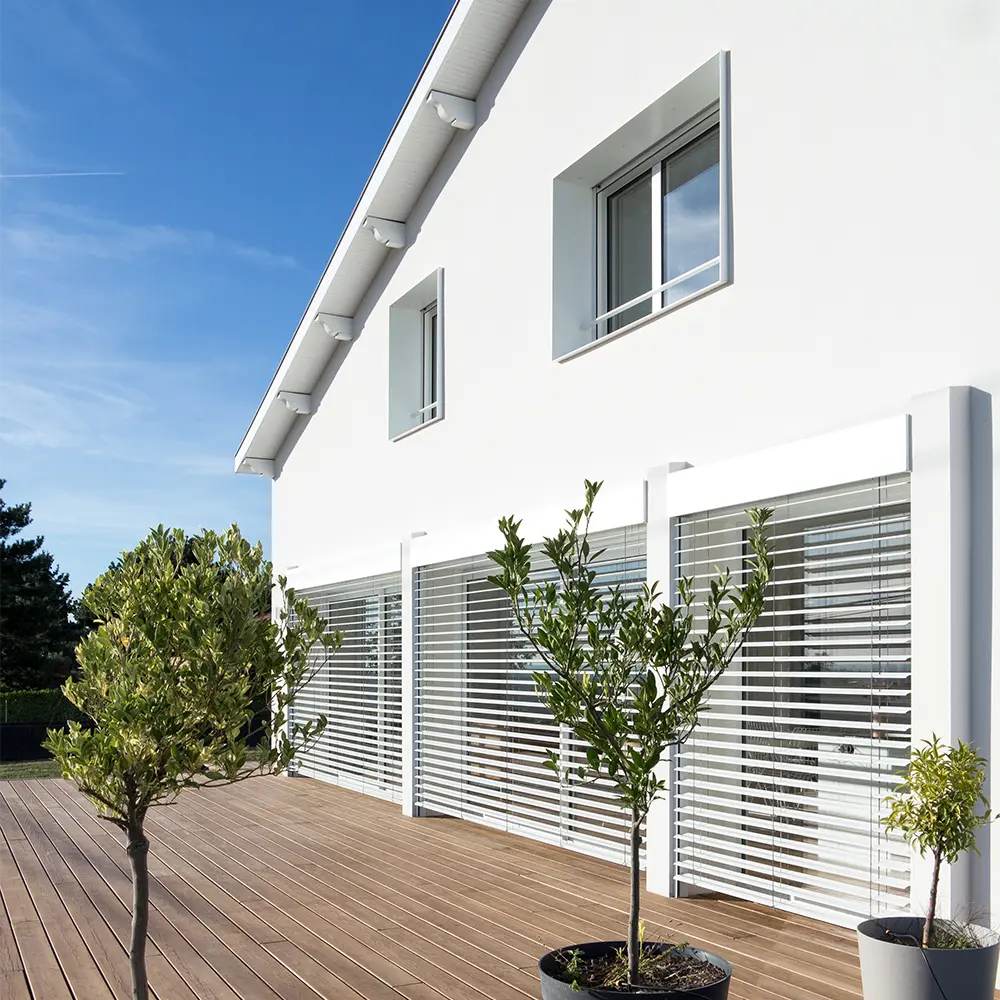 Façade de maison rénovée blanche et terrasse bois 